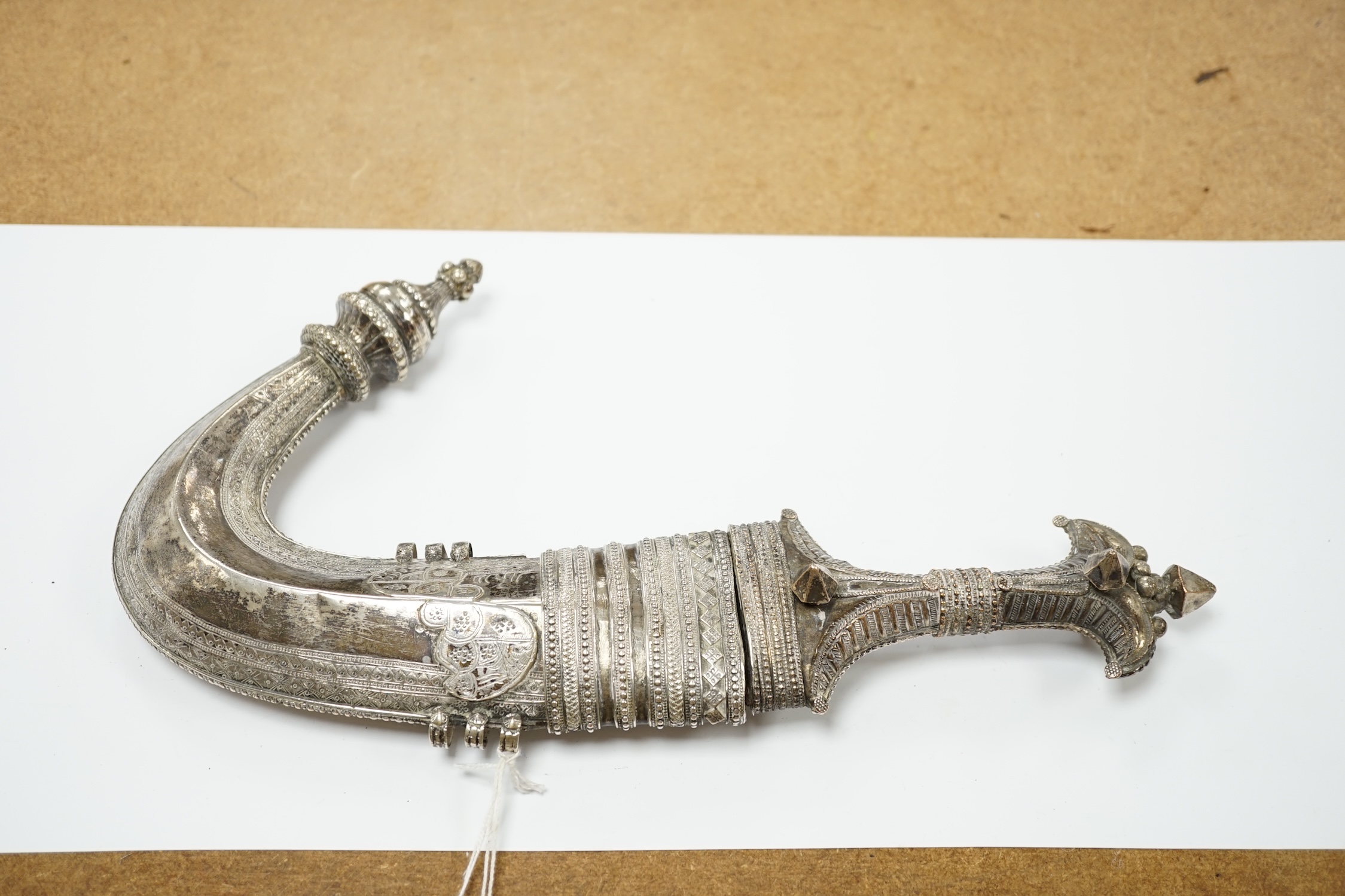 A composite Saudi dagger Jambiya c.1900, silver plated hilt, silver coloured metal sheath with engraved decoration. Condition - good, some wear